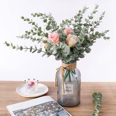 a vase filled with flowers sitting on top of a wooden table next to a plate