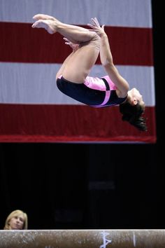 a woman on the balance beam in front of an american flag