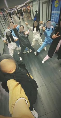 a group of people standing on top of a floor next to each other in front of a mirror