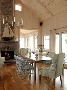 a dining room table with chairs and a fire place in the center is surrounded by windows