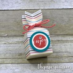 a small gift bag with the word enjoy on it sitting on top of a wooden table