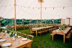 a large tent with tables and chairs set up for an outdoor wedding reception in the grass