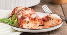 a white plate topped with lasagna covered in sauce and cheese next to a fork