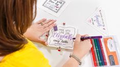 a woman is writing on a card with crayons