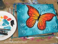 a butterfly painted on a canvas next to a plate with paint