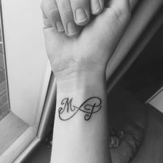 a black and white photo of a woman's wrist with the word mom tattooed on it