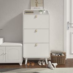 a white dresser sitting next to a baby's crib with shoes on the floor