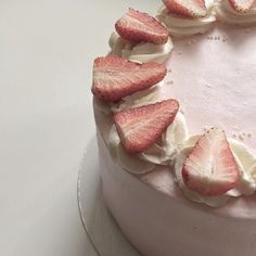 a white cake topped with sliced strawberries on top of it