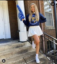 a woman in a blue sweatshirt and white skirt holding a skateboard on the steps