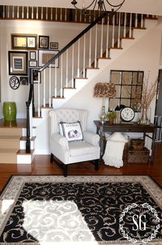 a white chair sitting in front of a stair case next to a table with a clock on it