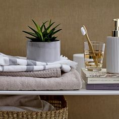 a white shelf topped with towels and a vase filled with plants