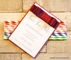 wedding stationery with colorful paper straws and ribbon tied around the top, on a brick wall