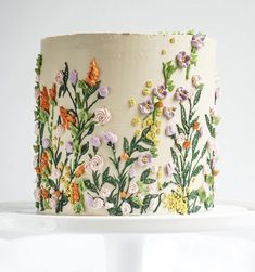 a white cake decorated with flowers and leaves