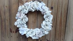 a wreath made out of seashells hanging on a wooden fence