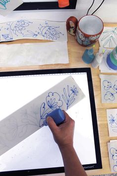 someone is drawing flowers on paper with blue marker and inking them onto a computer screen