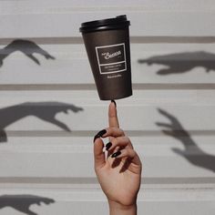 a woman's hand holding up a coffee cup with the shadow of dinosaurs on it