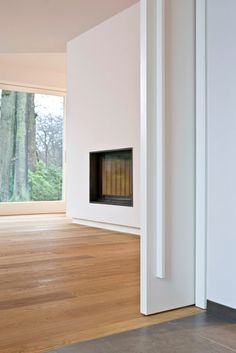 an empty room with wood flooring and a fire place in the corner near a window