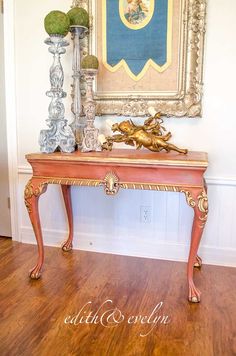 an ornate console table in the corner of a room with a painting on the wall