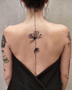 the back of a woman's neck with tattoos on her upper and lower back