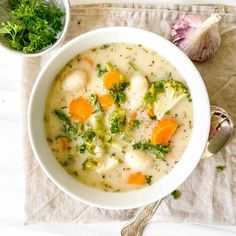 a white bowl filled with broccoli and dumpling soup next to a spoon