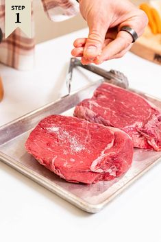 a person cutting up raw meat on a tray