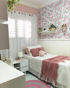 a bedroom with pink flowers on the wall and white bedding, rugs and curtains