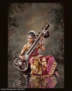 a woman sitting in the water holding an instrument