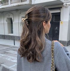 a woman with long hair wearing a gray sweater and leopard print bow tie on her head