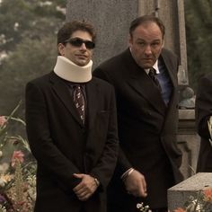 three men standing next to each other in front of a grave with flowers on it