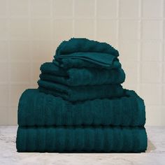 towels stacked on top of each other in front of a white tiled wall and floor