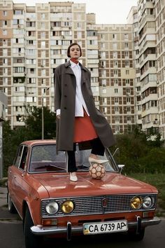 a woman standing on top of an old car