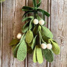 a green and white christmas ornament hanging from a wooden fence with holly leaves