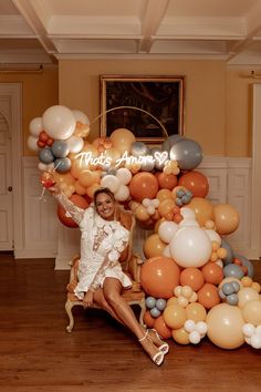 a woman sitting on a chair in front of a bunch of balloons that spell out thank you