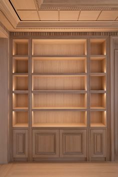 an empty bookcase in a room with wood paneling and lighting on the walls