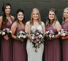 a group of women standing next to each other wearing dresses and holding bouquets in their hands