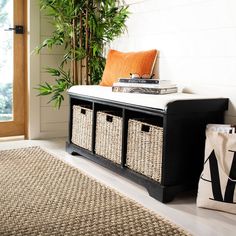 a black bench with baskets on it in front of a door and a plant next to it