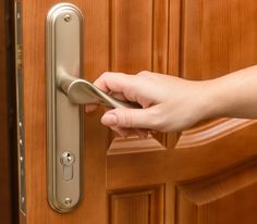 a person's hand is opening a door with a handle on the wooden door