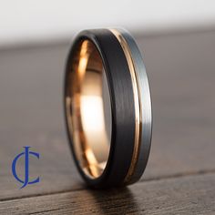 a wedding band with two tone gold and black inlays on a wooden surface