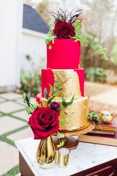 a three tiered cake sitting on top of a table next to two red roses