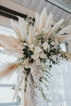 a tall white flower arrangement in front of a window