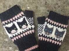 two knitted mittens with cats on them sitting on the ground next to each other