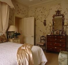 a bed sitting in a bedroom next to a dresser under a mirror on top of a wall