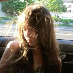 a woman sitting in the back seat of a car with long hair on her head