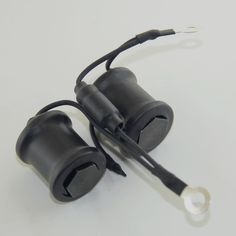 two black plugs connected to each other on a white surface with wires running through them