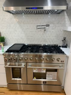 a stainless steel stove top oven sitting in a kitchen next to a wall mounted range