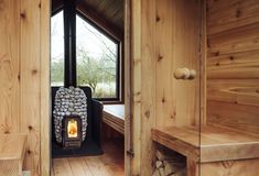 a wood burning stove sitting inside of a wooden room next to a bed and window