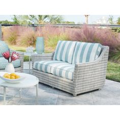 a couch and chair sitting on top of a patio next to a table with fruit