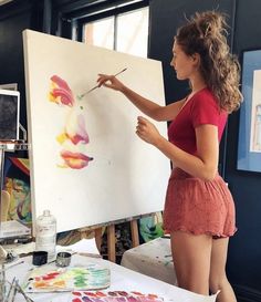 a young woman is painting on an easel