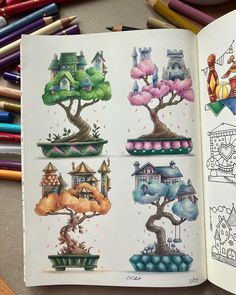 an open book with pictures of houses and trees on it next to colored crayons