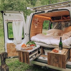 an open camper van with its bed pulled out and food in the cargo area